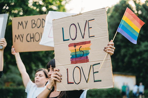 People are marching together at an LGBTQIA event, holding colourful signs. Gay pride event.