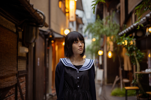 Woman walking in traditional Japanese narrow street in Kyoto, Japan