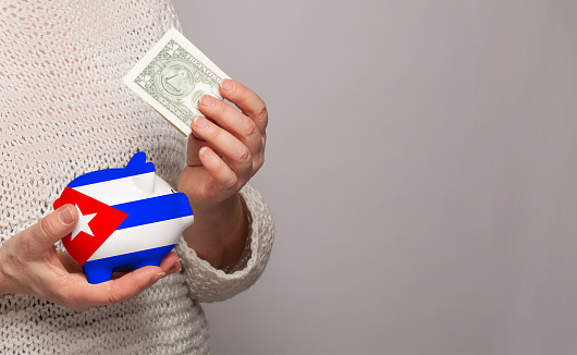 Flag of Cuba on money bank in Cuban woman hands. Dotations, pension fund, poverty, wealth, retirement concept