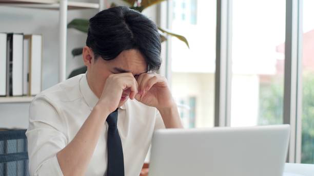 istock Young Asian man tired eyes from hard work. Young man tired feeling eyestrain stressed working from laptop. Suffers eyesight problem after using laptop for working long time 1496910193