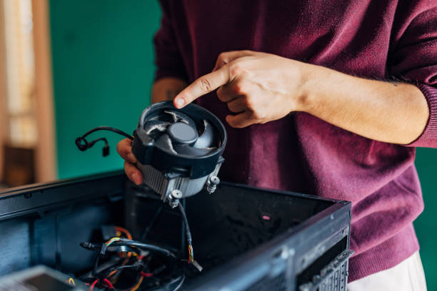 istock Close-up of a man's hands holding a computer cooler while repairing the computer at home 1496911586