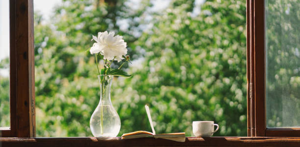 istock Book, cup coffee and white peonies on a wooden window. 1496913400