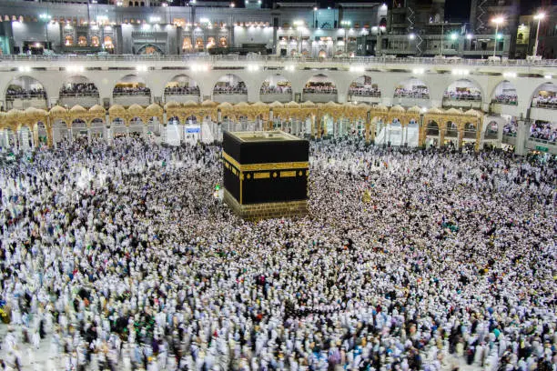 People walking around Holy Kaaba seven circles in Masjid Al Haram or Grand Mosque of Mecca, making Tawaf.
