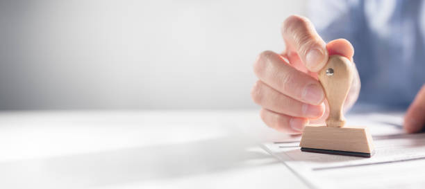 istock Businessman stamping approved rubber stamp on document in meeting background 1496915182