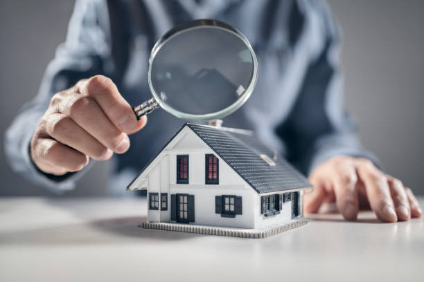 House model with man holding magnifying glass home inspection or searching for a house stock photo