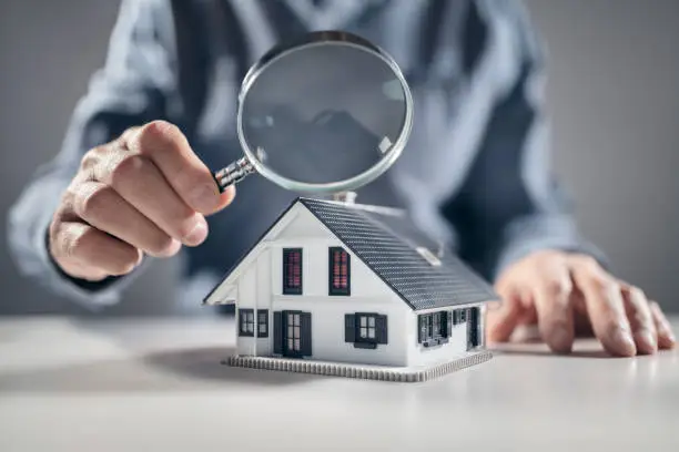 House with ith man holding magnifying glass concept for home inspection or searching for a new house