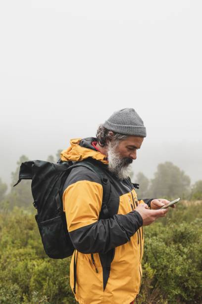 istock Man picking up the signal on his mobile phone and sending a voice message while hiking 1496916992