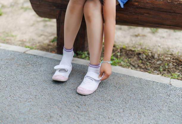 istock Little girl adjusts canvas shoes 1496919648