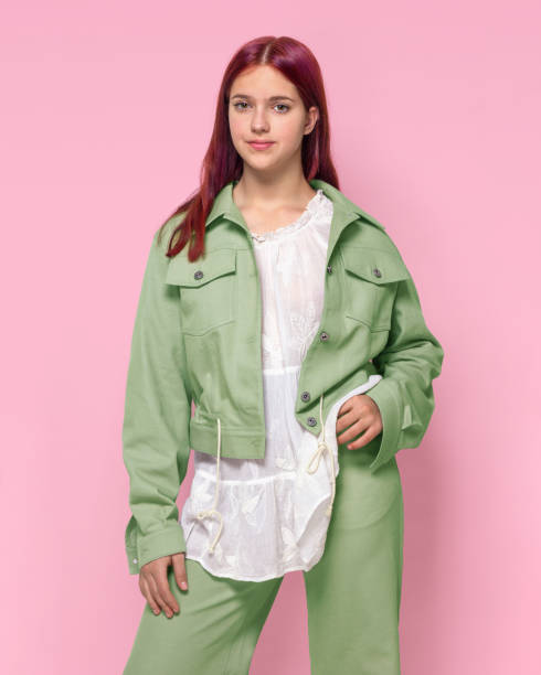 istock A girl in a light green oversized denim suit on a pink background studio isolated. 1496920180