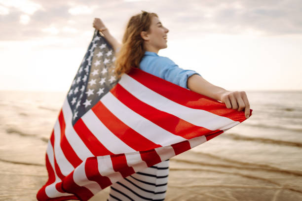 istock Young woman with American flag on the beach. 1496920754