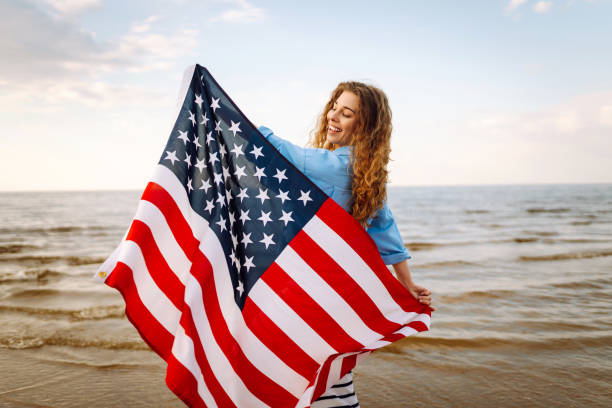 istock Young woman with American flag on the beach. 1496920766