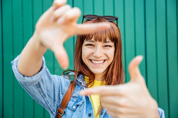 Young pretty woman making frame shape with hands on a green background
