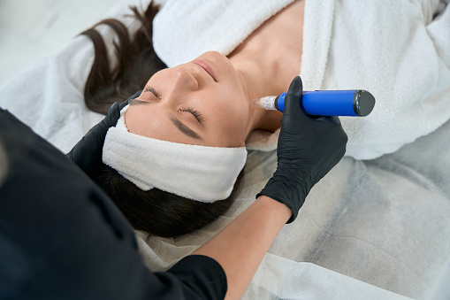 Dermatólogo sosteniendo el dispositivo y realizando el procedimiento de rejuvenecimiento de la piel photo