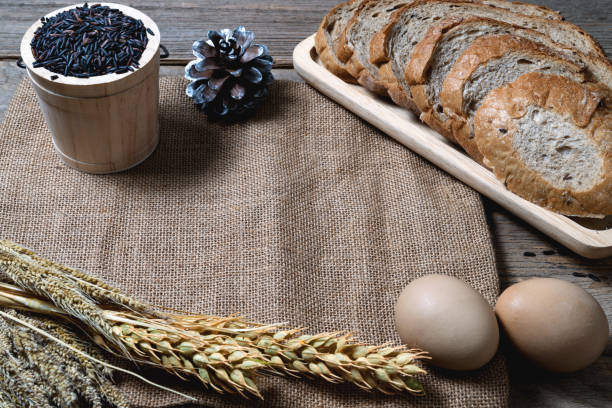 bread loaf and wheat ears and sack on wooden background.