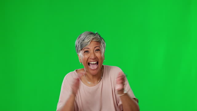 Senior woman, excited and applause on green screen, celebrate winning with happiness and dancing. Cheers, female jump with happy dance and celebration, promotion and bonus mockup on studio background