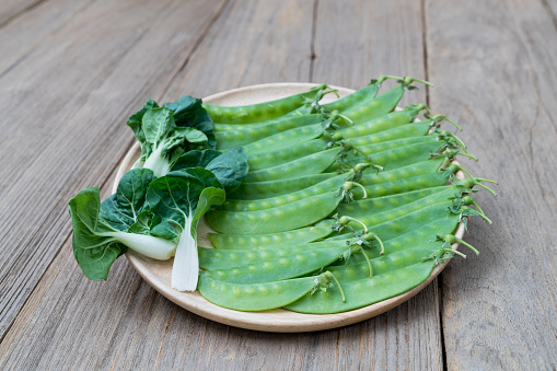 Peas and Pak choi on wooden dish