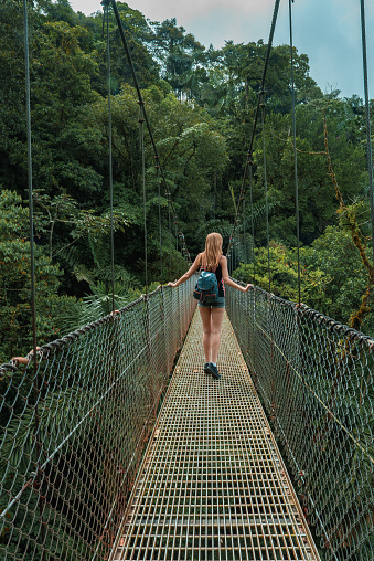 Arenal Hanging Bridges, young woman hiking in green tropical jungle, Costa Rica, Central America.