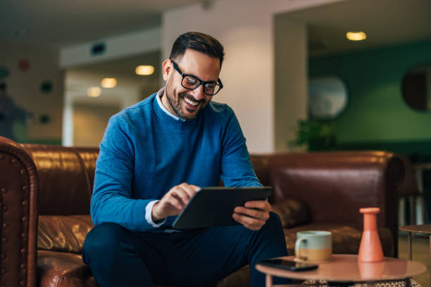 istock Smiling businessman using a digital tablet, sitting on the leather sofa. 1496936183