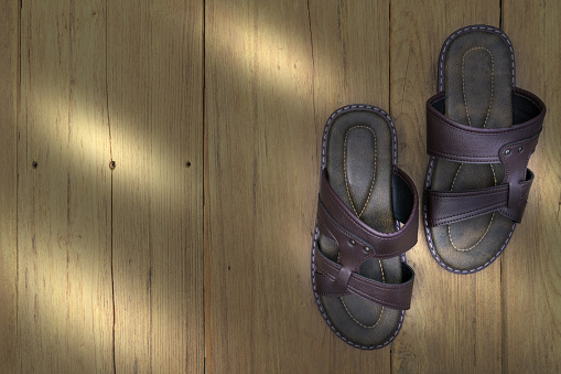 Brown leather slippers on wood background,top view
