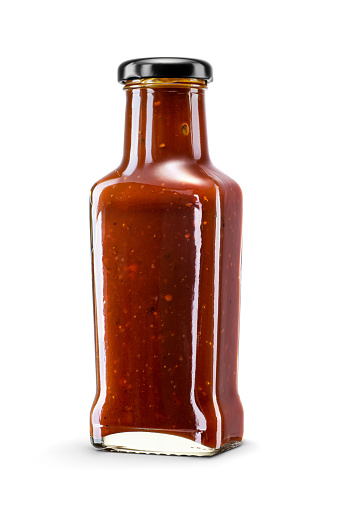 Glass bottle of tomato barbecue sauce for meat isolated on white background with clipping path. Popular condiment used in a variety of dishes.