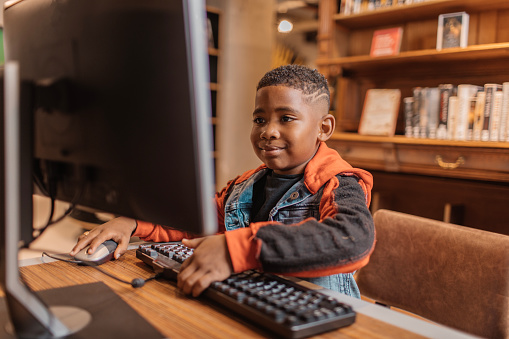 A young black reader using a computer in a library