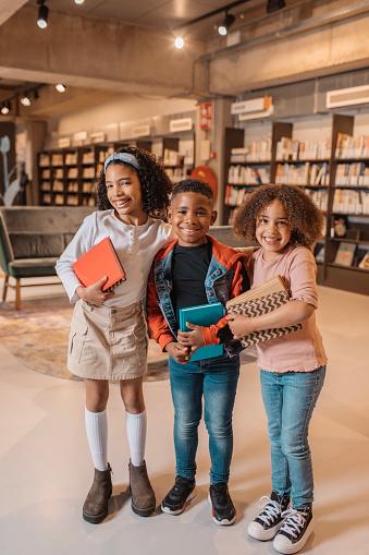 Three young black and diverse school children in a library