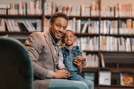 A young adult black teacher with diverse child reader in a library