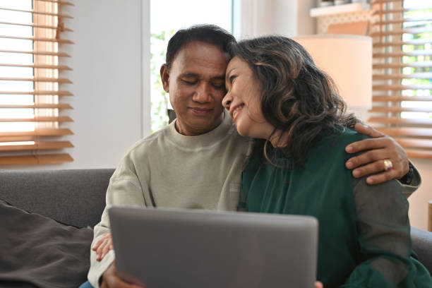 istock Asian retired couple smiling happily inside their home, Elderly Fund, Pension retirement insurance concept. 1496942165