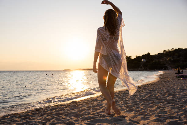 istock Unrecognizable young woman in a sundress on the beach during sunset 1496942709