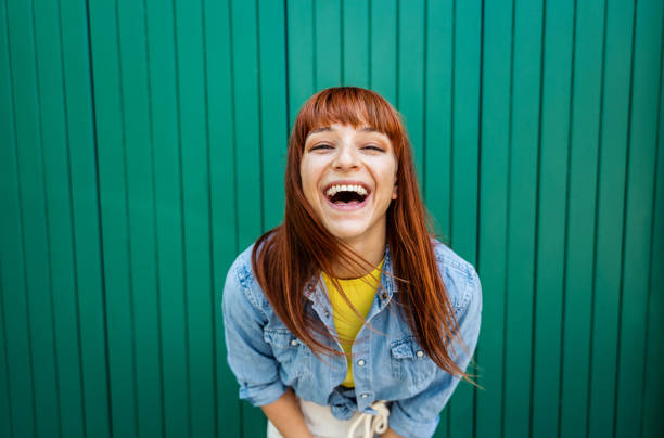 カメラで笑う若い美しい白人の赤い髪の女性 – ポートレートの緑の背景 - 笑う ストックフォトと画像
