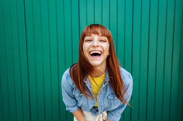 young beautiful caucasian red hair woman laughing at the camera - portrait green background - rir imagens e fotografias de stock