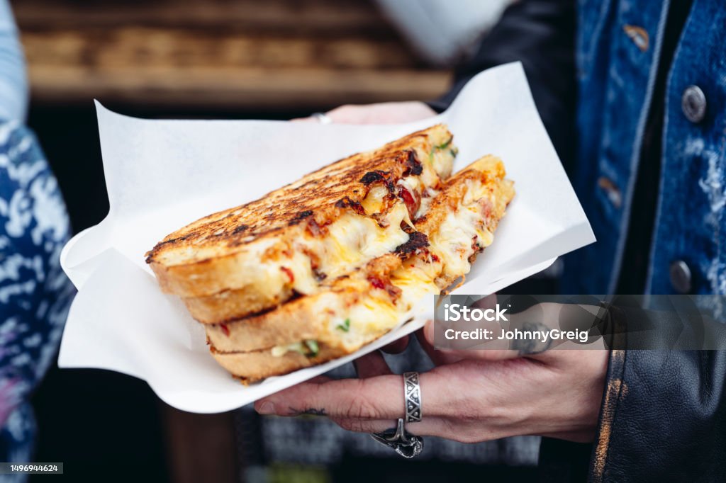 Outdoor portrait of grilled cheese sandwich Close view of young adult holding toasted street food. Brick Lane - Inner London Stock Photo
