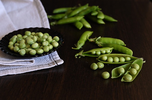 Green shoots of young peas, flowers and pods on a dark wooden background. selective focusing