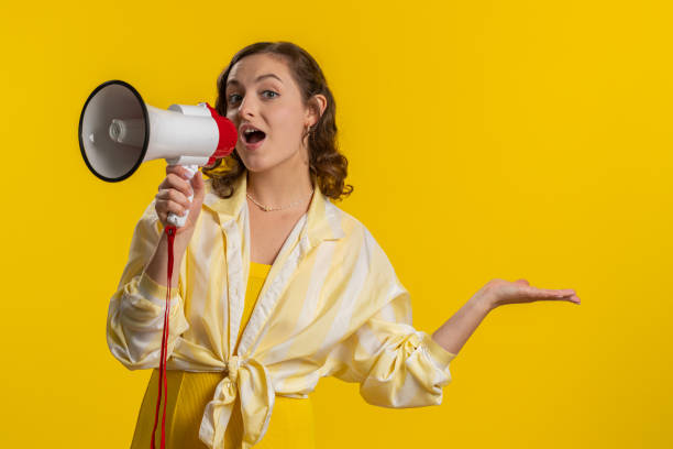 istock Woman talking with megaphone, proclaiming news, loudly announcing advertisement pointing empty place 1496947428