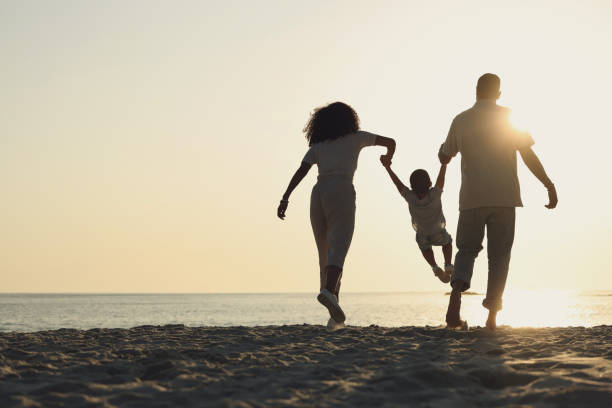 istock Silhouette, mockup and a family on a beach, playing while having fun together by the ocean or sea. Kids, travel or love with a mother, father and child on the sand at sunset to play while bonding 1496948614