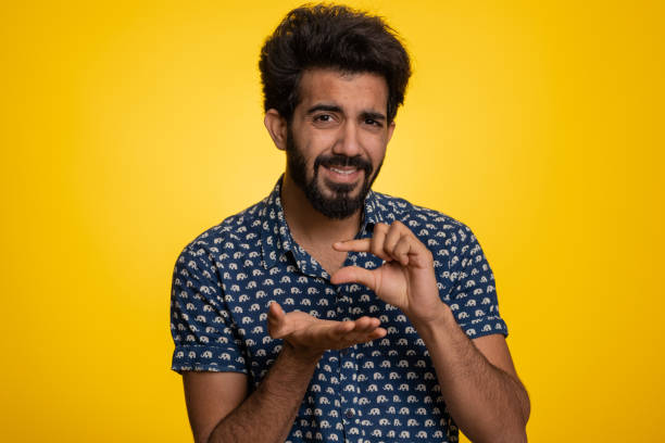 istock Indian man showing a little bit gesture with sceptic smile showing minimum sign measuring small size 1496949780