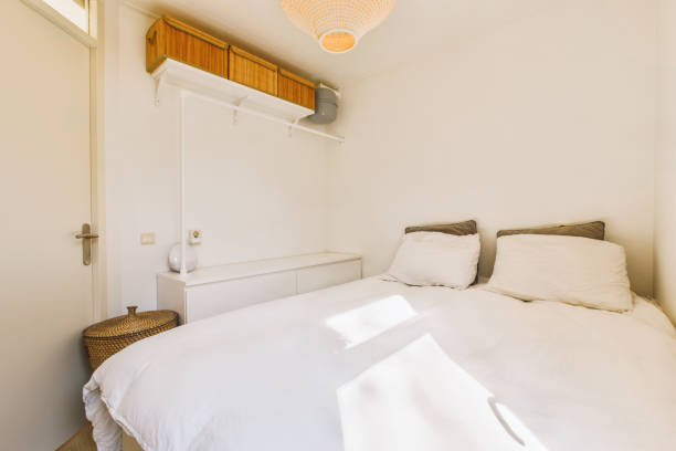istock a small bedroom with a white bed and a window 1496951938