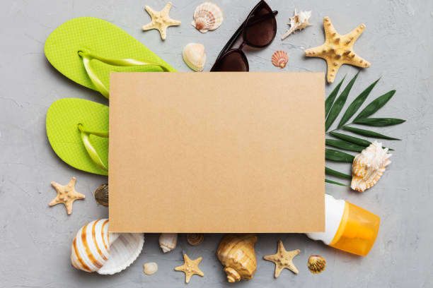 istock Summer time concept with blank greeting card and blank craft paper on colored background. Seashells from ocean shore in the shape of frame separated with space for text top view 1496954248