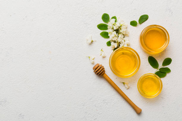 アカシアの花と葉の入った蜂蜜の瓶。新鮮な蜂蜜トップビューフラットレイ - spoon honey cute jar ストックフォトと画像