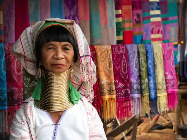 Karen Long Neck woman wearing traditional brass rings and selling handicrafts in hill tribe village near Chiang Rai, Thailand.
