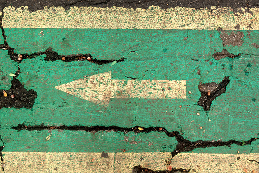A white arrow painted on the ground, on a bicycle lane.