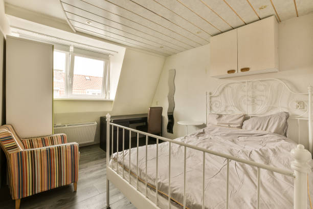 istock a small bedroom with a white bed and a chair 1496959563