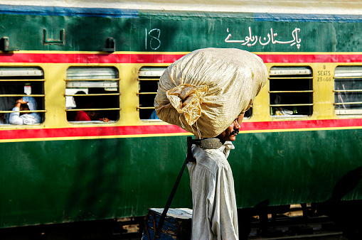 Pakistan, Karachi - March 25, 2005: Man carrying a sack on his head at the train station in Pakistan