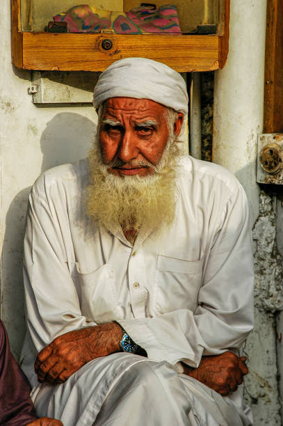 Pakistan, Karachi - March 25, 2005: An old man with a beard sitting on the street