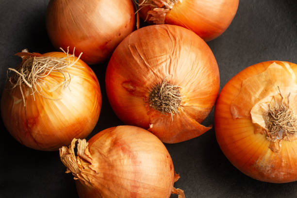 istock Six onions on a dark background in a top view 1496963423