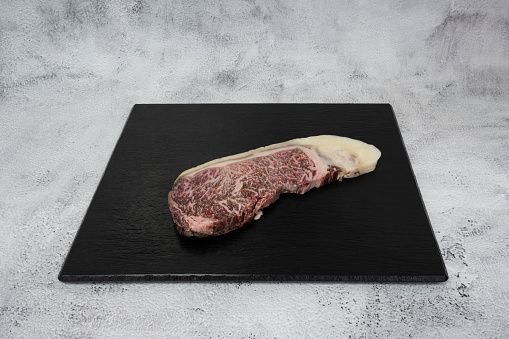 French culinary Still Life. Piece of Wagyu beef sirloin placed on a black tile top.