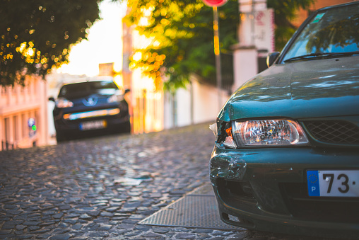 Lisbon, Portugal - July 24 2016: Green portuguese car with damage to the front bumper and signal light on a narrow street.