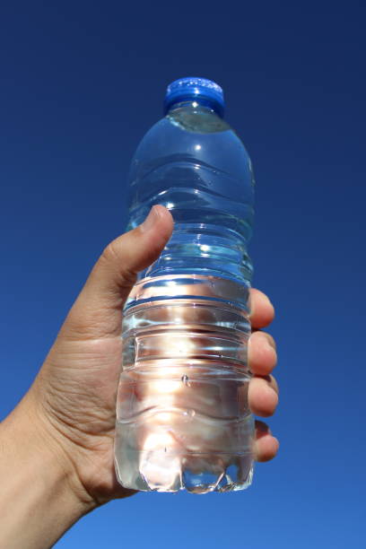 istock water in plastic bottle in man's hand on sky background 1496970416