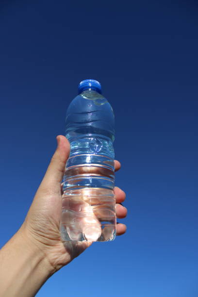 istock water in plastic bottle in man's hand on sky background 1496970423