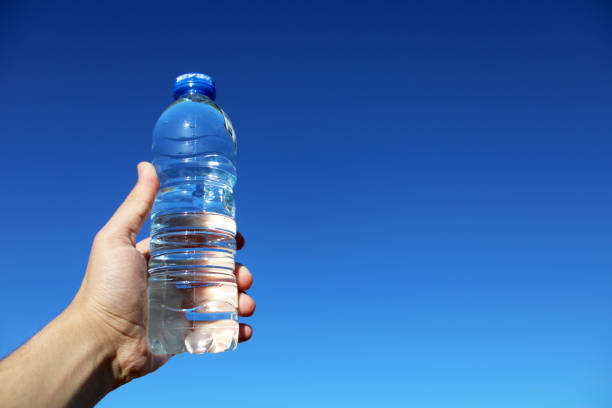 istock water in plastic bottle in man's hand on sky background 1496970466